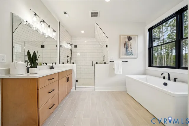 a spacious bathroom with double vanity a large mirror a vanity and a bathtub