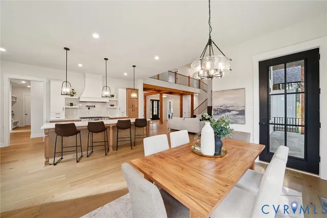 a dining room with wooden floor potted plants and a chandelier