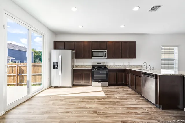 a kitchen with stainless steel appliances wooden cabinets a refrigerator and a stove top oven
