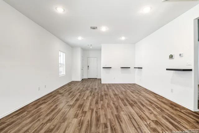 a view of empty room with wooden floor and window