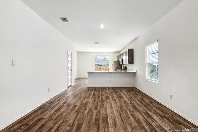 a view of empty room with wooden floor and window