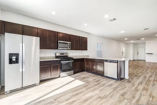 a kitchen with stainless steel appliances kitchen island granite countertop a refrigerator and a stove top oven