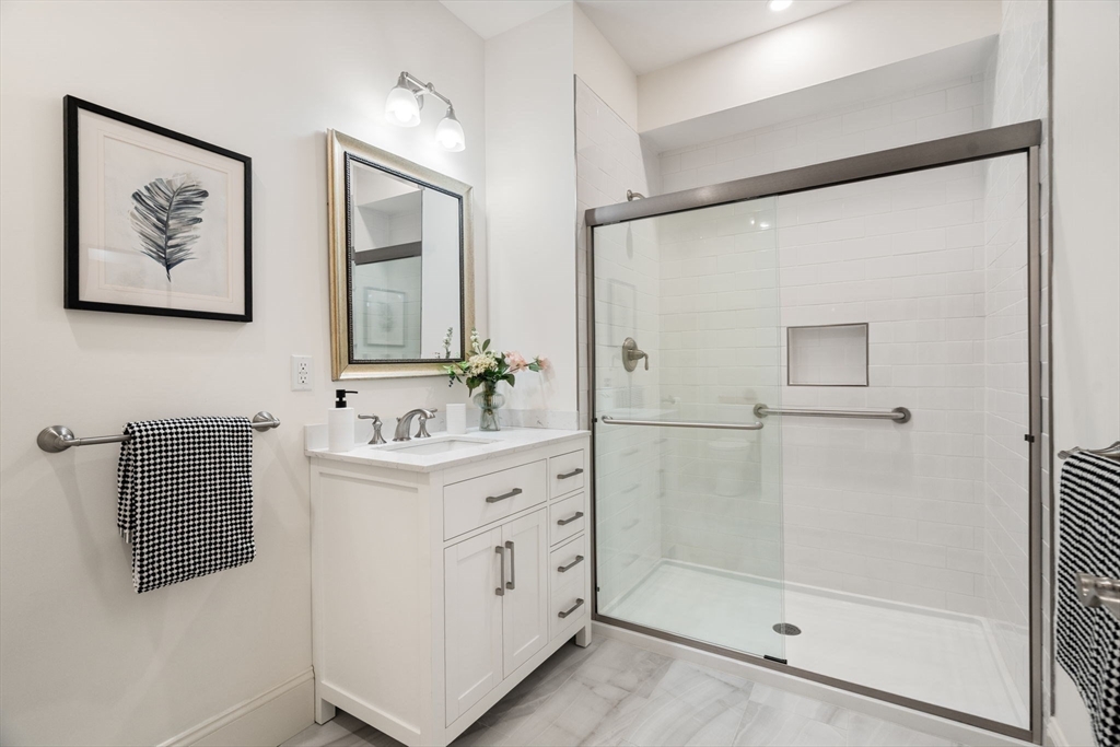 287 Langley Road, Unit 43 Newton, MA 02459 - Photo 19 of 36 a bathroom with a bathtub a shower a sink and mirror