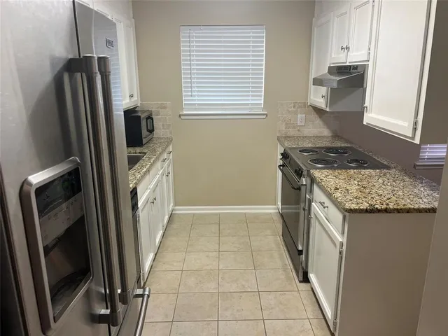 a kitchen with stainless steel appliances granite countertop a refrigerator a stove and a sink