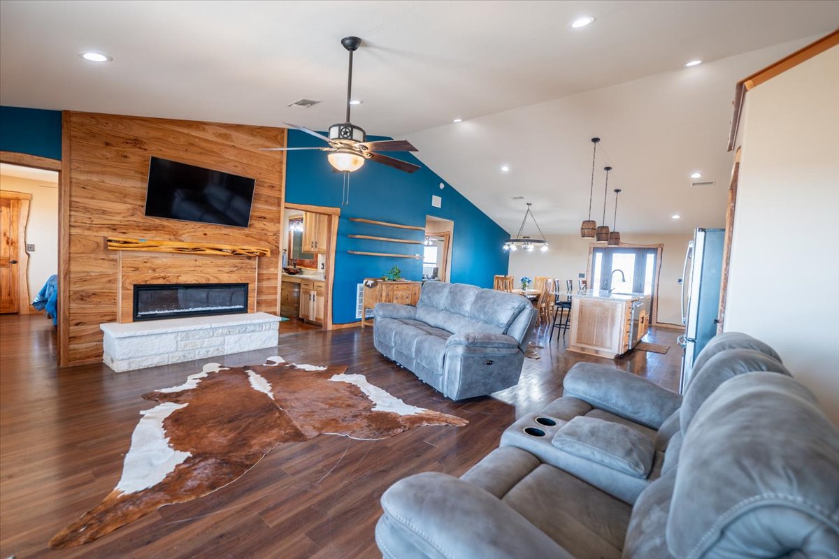 1825 Savanna Ridge Ranch Road Lometa, TX 76853 - Photo 7 of 35 Living area featuring lofted ceiling, a large fireplace, wood finished floors, recessed lighting, and wooden walls