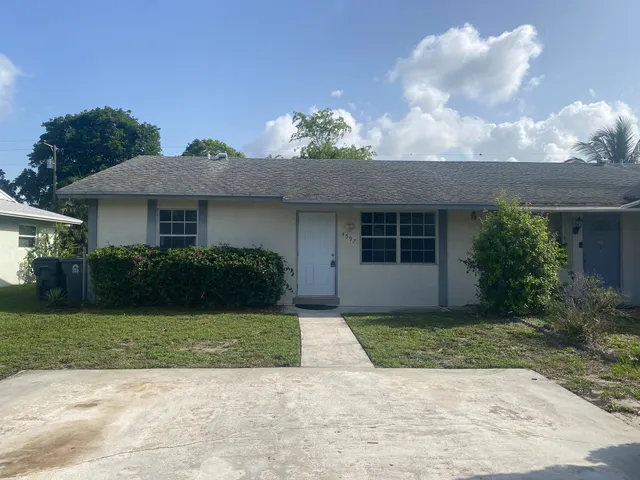 a front view of a house with a yard and potted plants