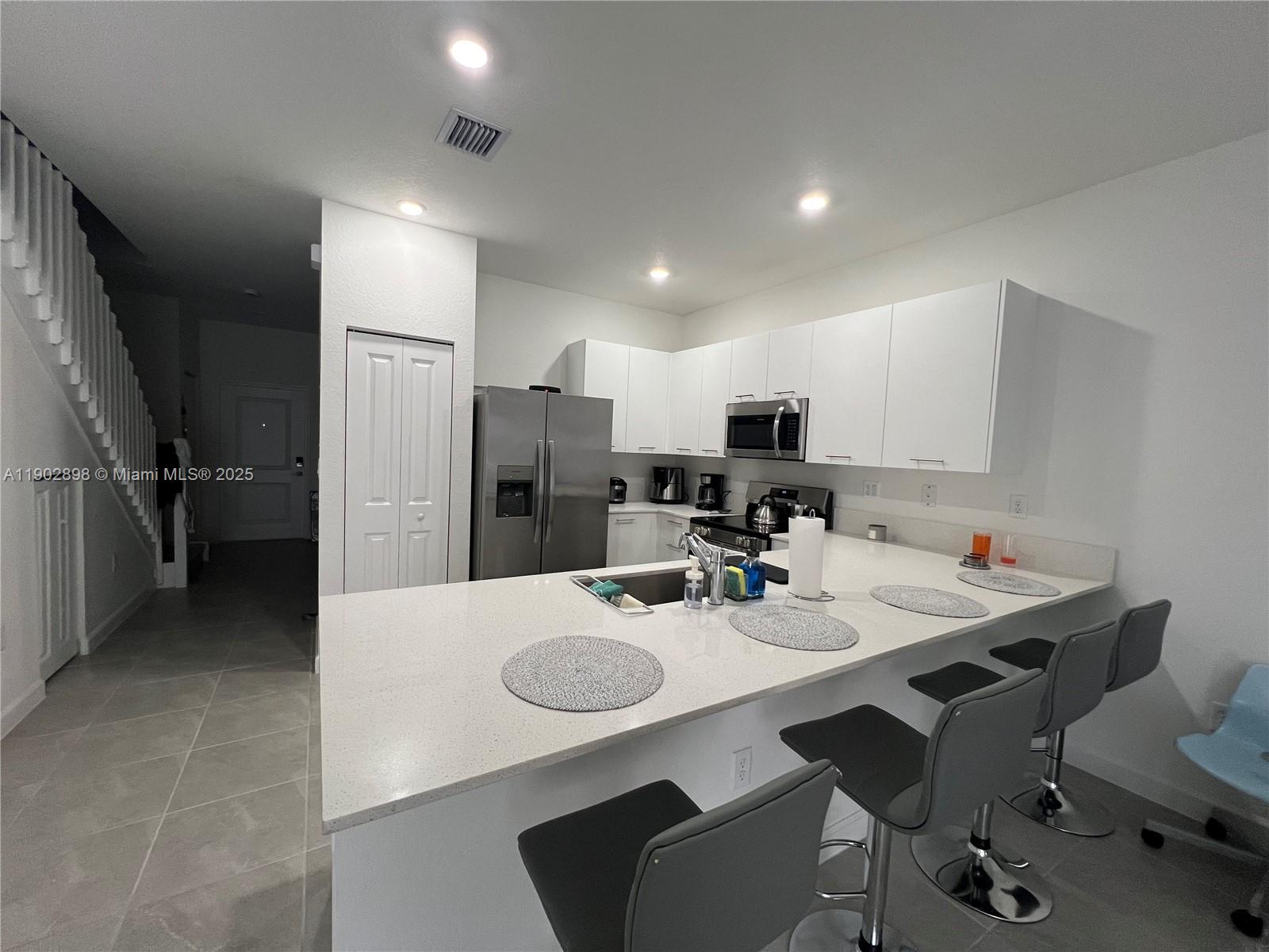 12142 Northwest 24th Court Miami, FL 33167 - Photo 19 of 20 a kitchen with refrigerator and chairs