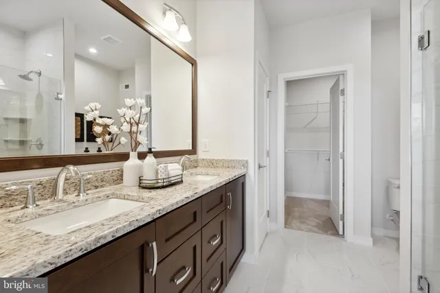 a bathroom with a granite countertop double vanity sink and a mirror