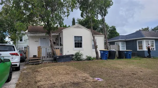 a view of a house with a yard and large tree