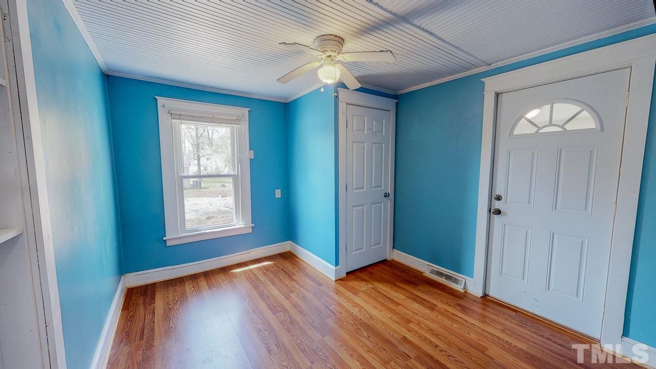 7089 Virgilina Road Roxboro, NC 27574 - Photo 17 of 28 an empty room with wooden floor chandelier fan and windows