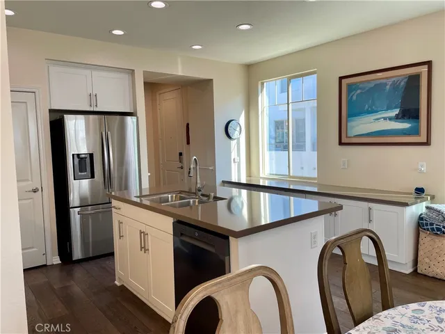 a kitchen with stainless steel appliances granite countertop a refrigerator a sink a stove and wooden floor