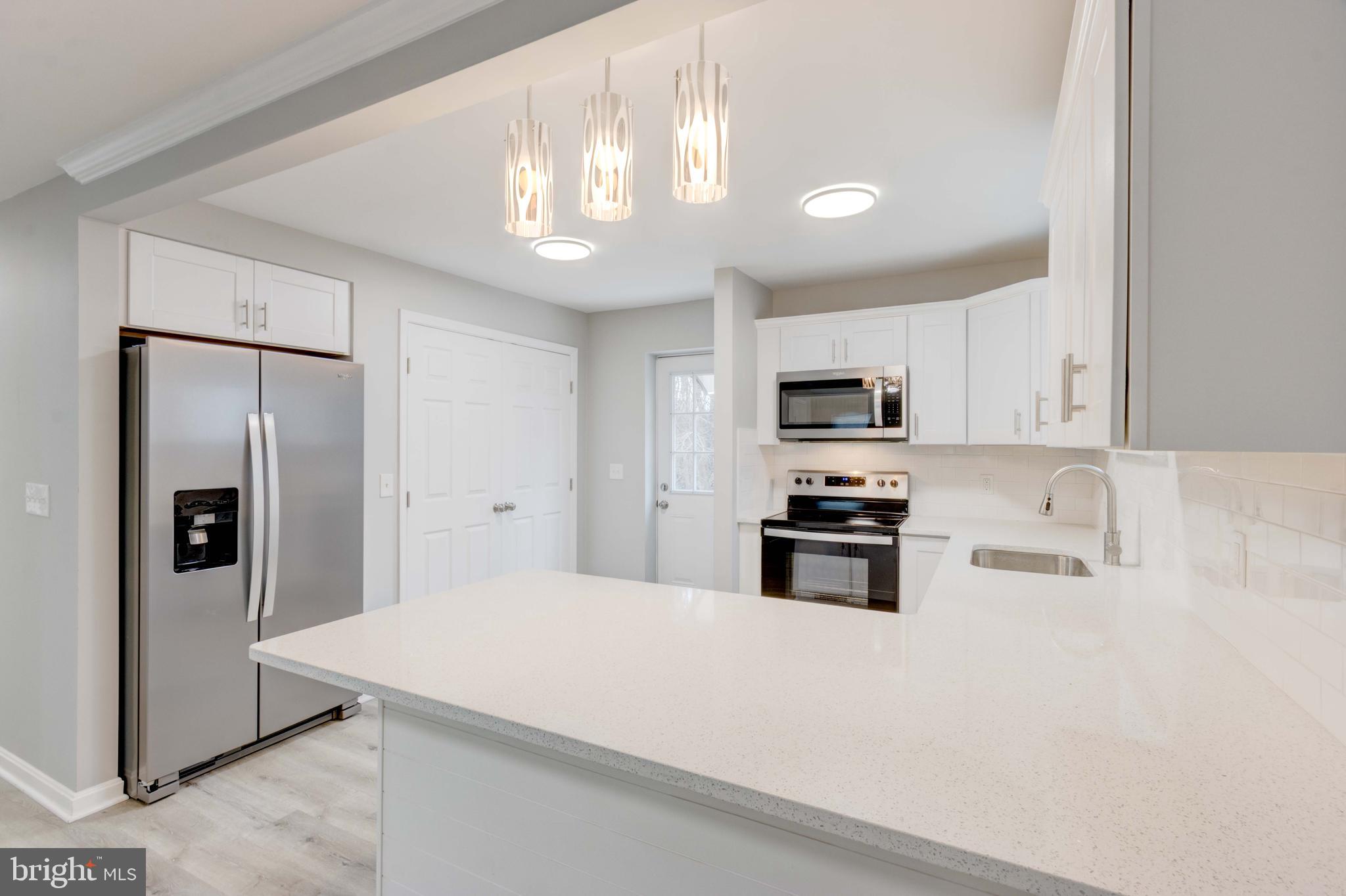 8149 Hog Neck Road Pasadena, MD 21122 - Photo 8 of 24 a kitchen with stainless steel appliances a refrigerator a stove a microwave and cabinets