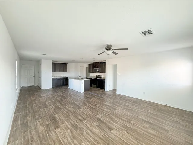 a view of kitchen and empty room with wooden floor