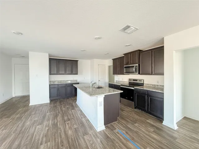 a kitchen with stainless steel appliances a stove top oven a sink dishwasher and a refrigerator with wooden floor