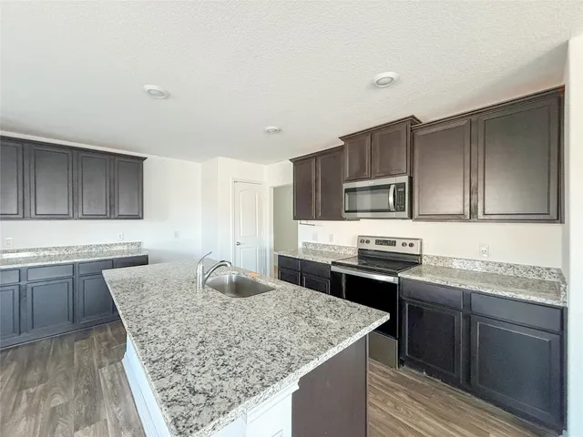 a kitchen with stainless steel appliances granite countertop a sink stove microwave and cabinets