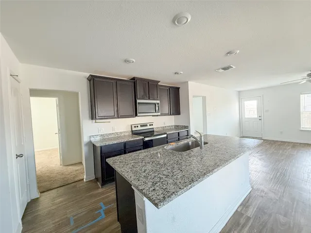 a kitchen with granite countertop kitchen island a counter space a sink and appliances