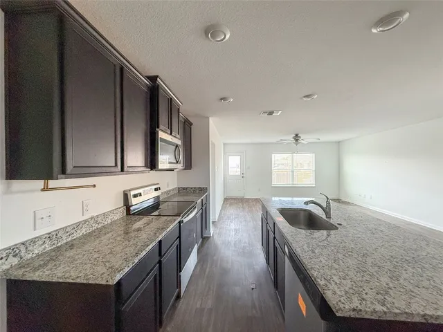 a kitchen with granite countertop stainless steel appliances sink stove microwave and cabinets