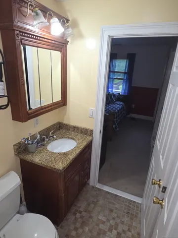 a bedroom with a bed a chair and next to a window