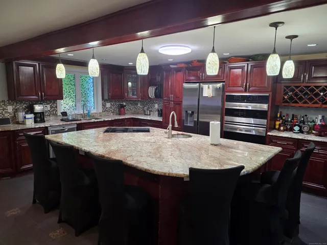 a kitchen with a sink a counter space appliances and a view of living room