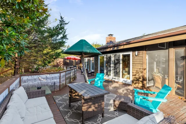 a view of a patio with couches table and chairs under an umbrella with a barbeque