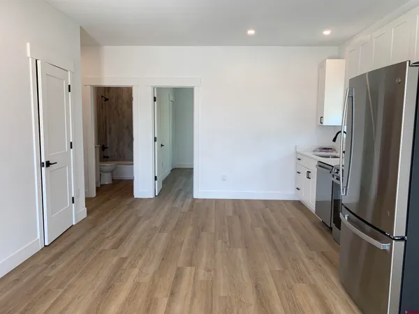 a view of a kitchen with a refrigerator wooden floor and a sink