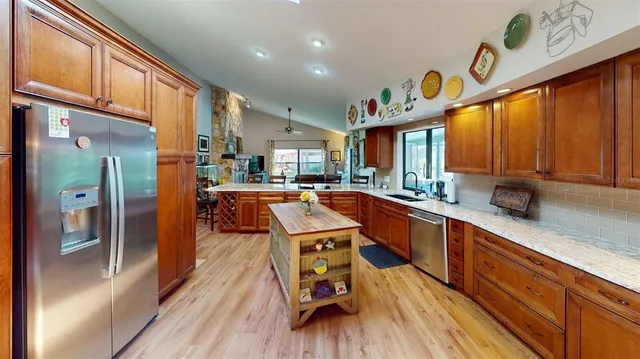 a large kitchen with stainless steel appliances wooden floors and a large window