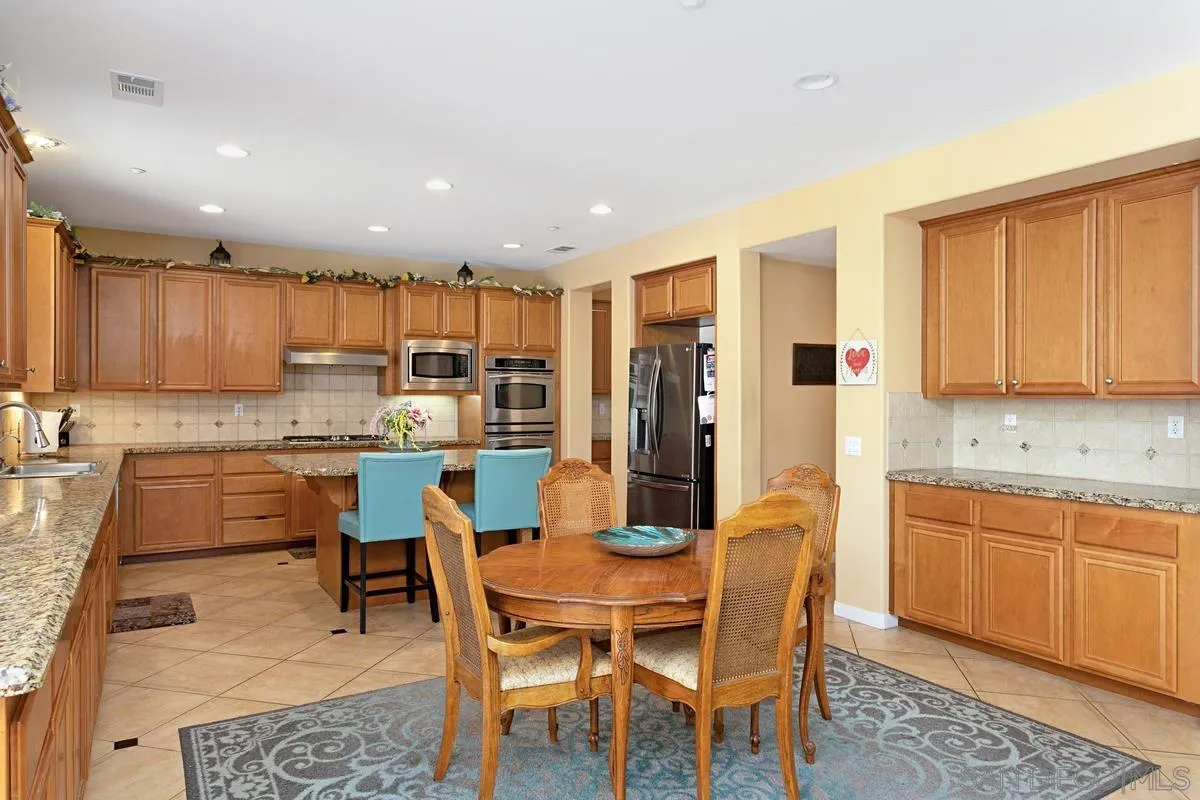 604 Hidden Trails Road Escondido, CA 92027 - Photo 12 of 49 a kitchen with a dining table chairs and refrigerator