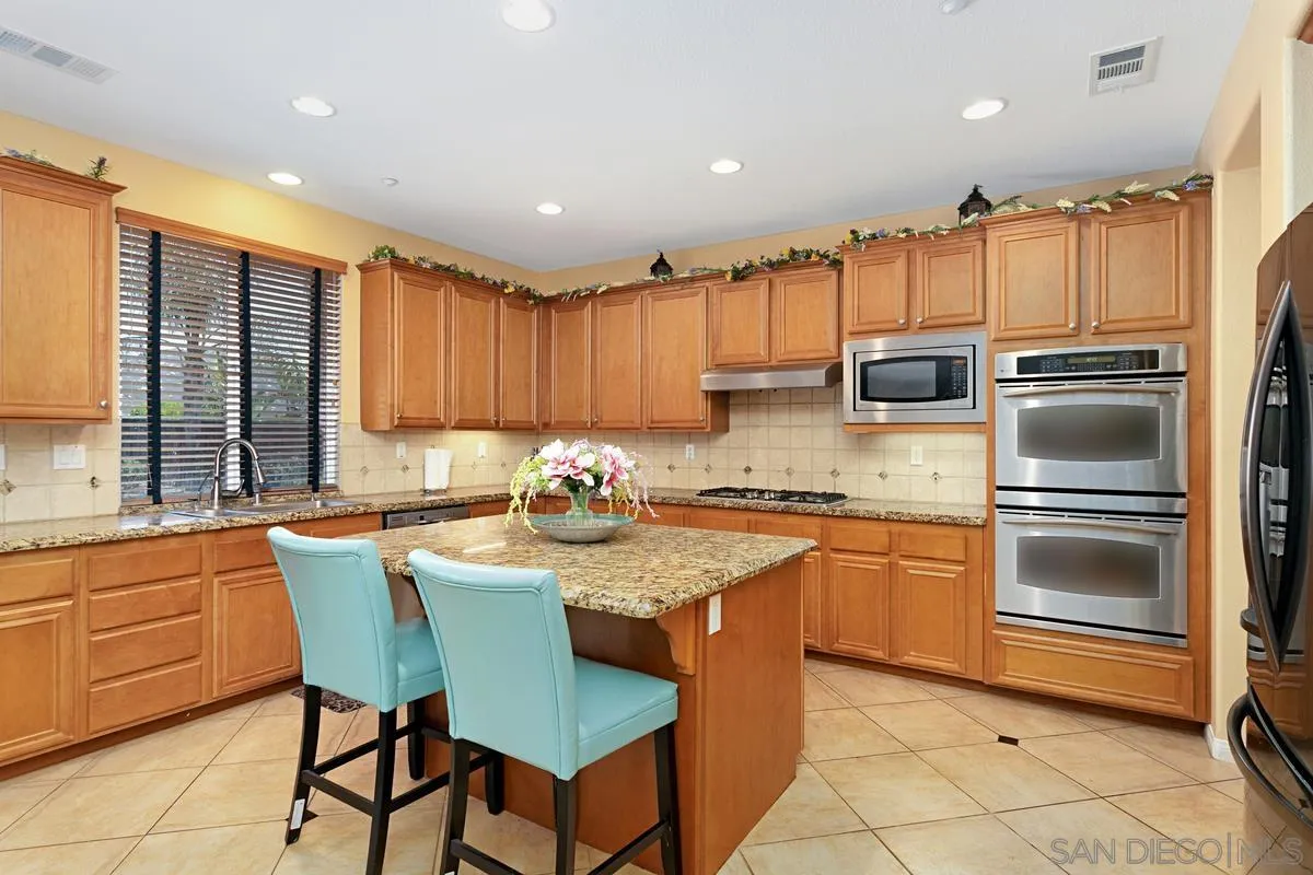 604 Hidden Trails Road Escondido, CA 92027 - Photo 13 of 49 a kitchen with stainless steel appliances granite countertop a stove a sink a microwave and a refrigerator