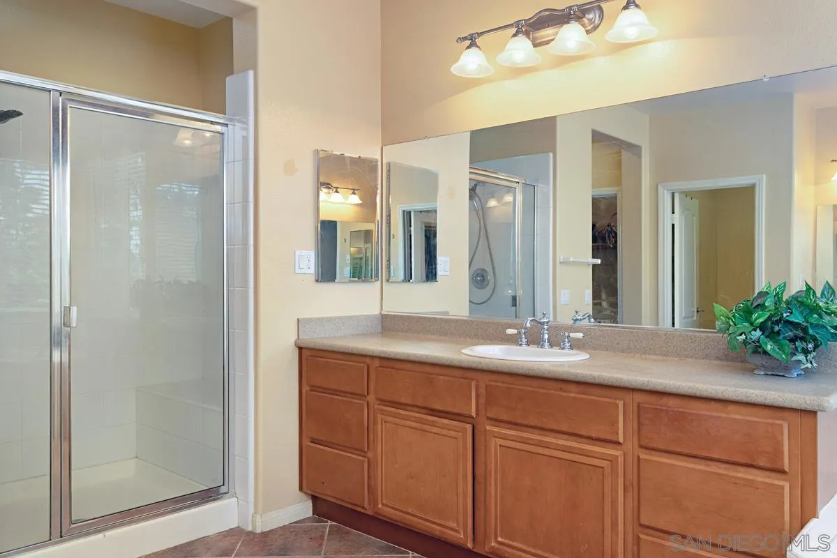 604 Hidden Trails Road Escondido, CA 92027 - Photo 36 of 49 a bathroom with a granite countertop sink a mirror and a shower