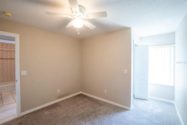an empty room with a ceiling fan and a window