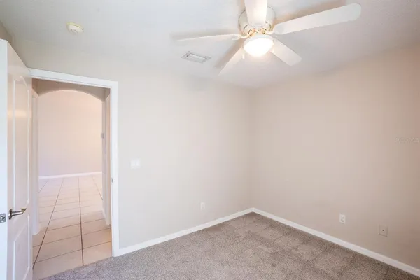 an empty room with a fan & a ceiling fan