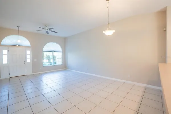 an empty room with windows and ceiling fan