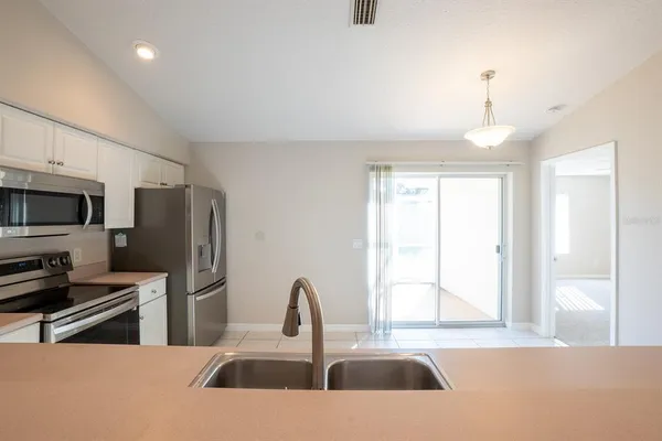 a kitchen with stainless steel appliances a sink a microwave a refrigerator and cabinets