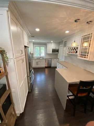 a kitchen with refrigerator a sink and chairs