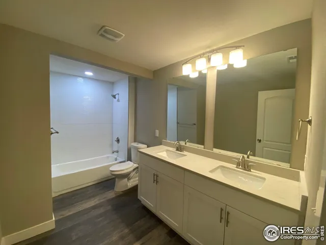 a bathroom with a double vanity sink toilet mirror and bathtub