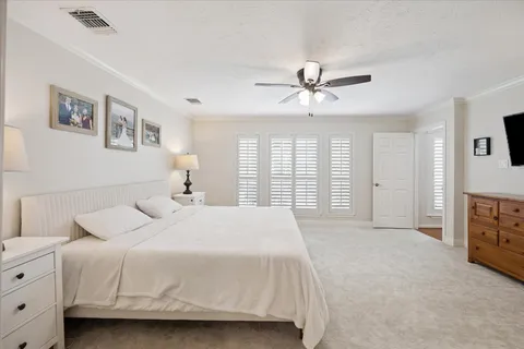 a spacious bedroom with a bed a dresser and a chandelier