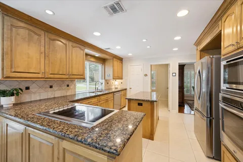 a kitchen with stainless steel appliances granite countertop a sink a stove and a refrigerator