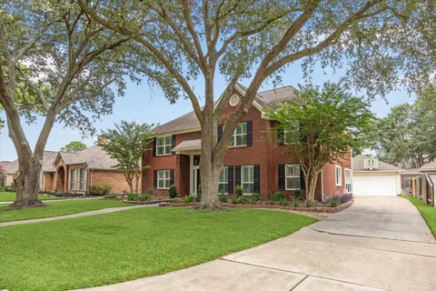 a front view of a house with a garden and trees