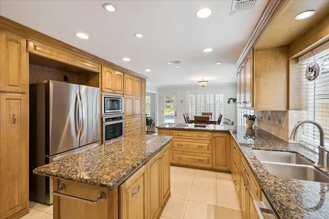 a large kitchen with kitchen island a large counter top stainless steel appliances and cabinets
