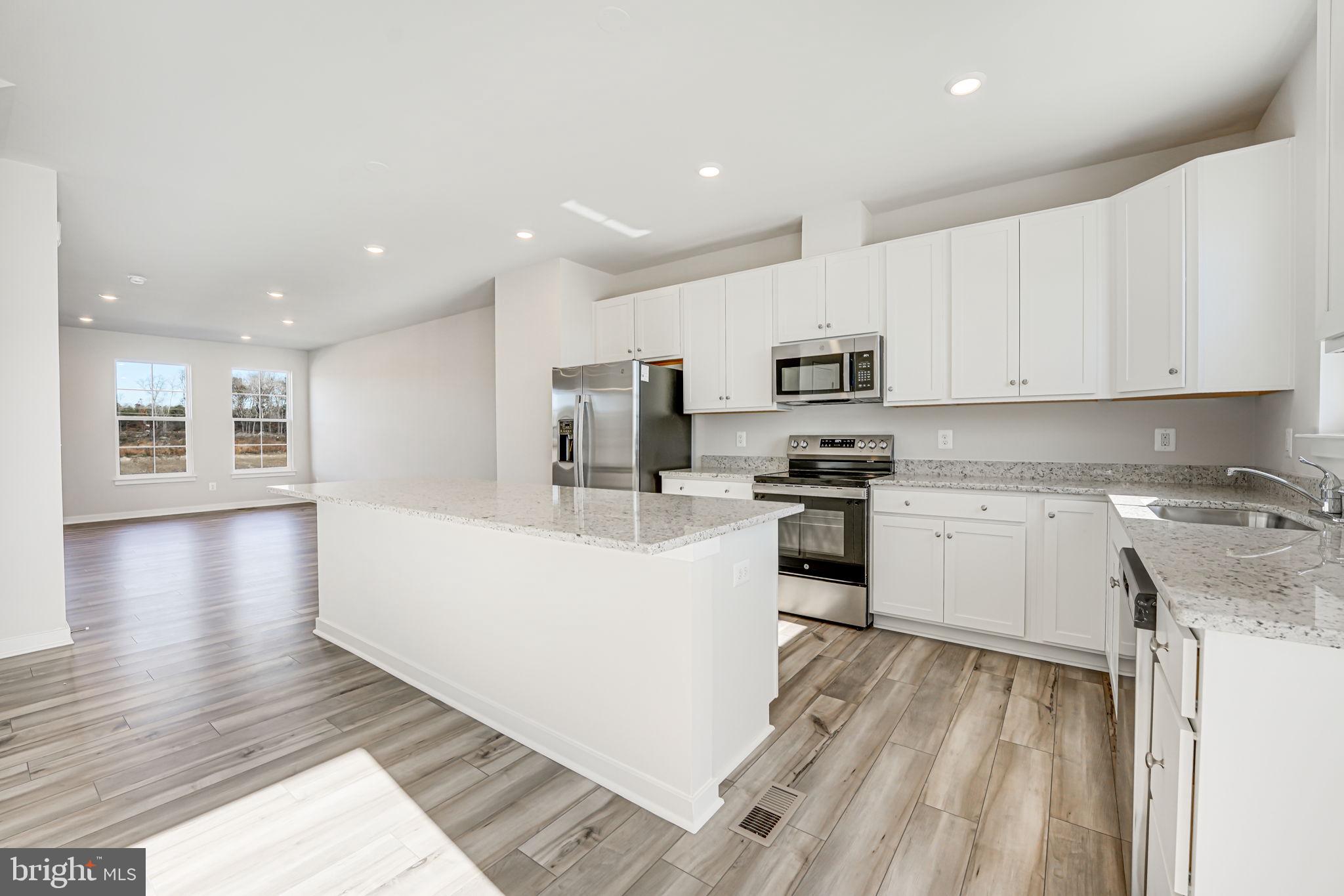 19122 Isabel Boulevard Appomattox, VA 24522 - Photo 11 of 35 a large kitchen with stainless steel appliances granite countertop a stove a sink a refrigerator and white cabinets with wooden floor