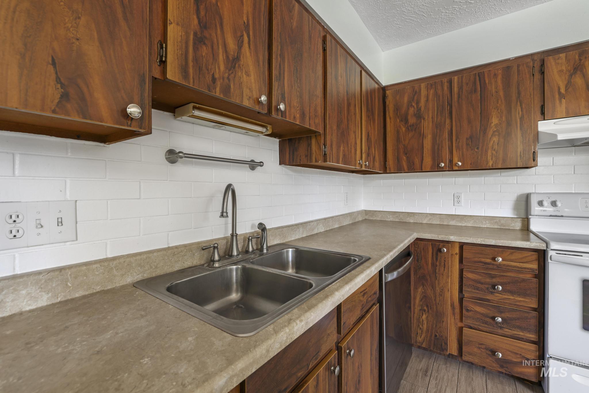 712 Locust Street Kimberly, ID 83341 - Photo 11 of 26 Kitchen featuring wood-finish cabinetry, white tile backsplash, and light-toned countertops