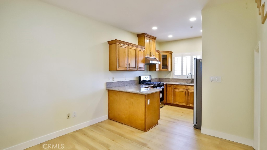 12388 Arrowhead Street Stanton, CA 90680 - Photo 18 of 69 a kitchen with stainless steel appliances granite countertop a sink a stove top oven a wooden floor a dining table and chairs
