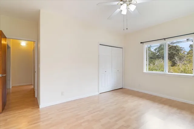 an empty room with a chandelier fan and windows