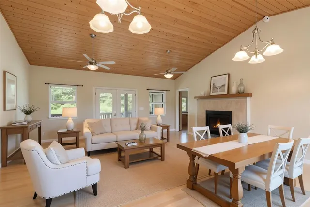 a living room with furniture a fireplace and a dining table with wooden floor