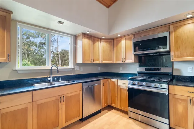 a kitchen with granite countertop a stove a sink and a microwave