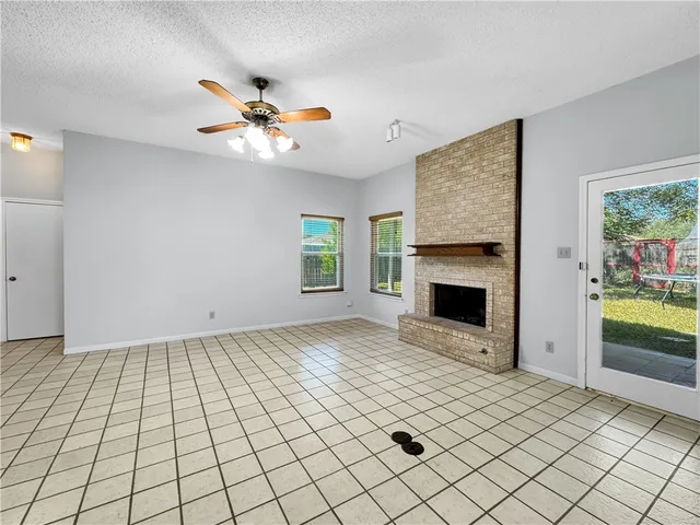 a view of an empty room with a fireplace and a window