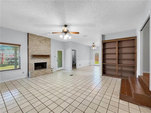 a view of an empty room with a fireplace and a window