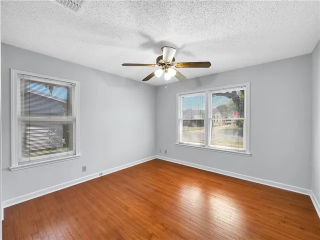 a view of an empty room with a window and wooden floor