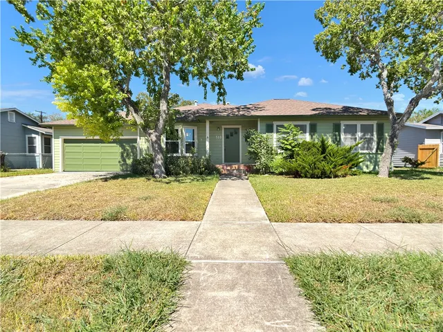 a front view of a house with a yard and potted plants