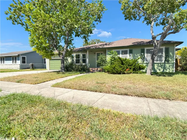 a front view of a house with a yard and potted plants